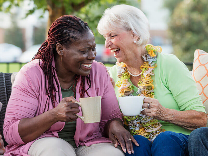 two women drinking coffee outside